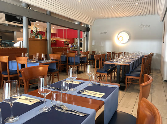Im Vordergrund des Restaurant-Bereichs befindet sich einer vom mehreren mit dunkel- und hellblauen Unterlagen dekorierter Tisch.
