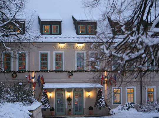 Großes, abendlich beleuchtetes Schlosshotel voller Schnee.