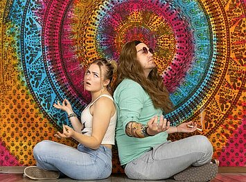 zwei meditierende Hippies vor bunter Wand