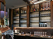 Schön in Szene gesetzte Bar mit einer großen Spiegelwand vor der die alkoholischen Flaschen stehen sowie die frischen Gläser.