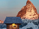 Kleine Holzhütte vor einem Berggipfel