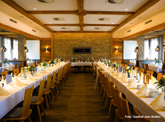 Blicken in den langen Gastraum mit festlich gedeckten Tafeln