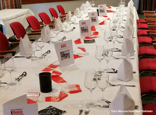 eine in weiß gedeckte Tafel mit roten Stühlen