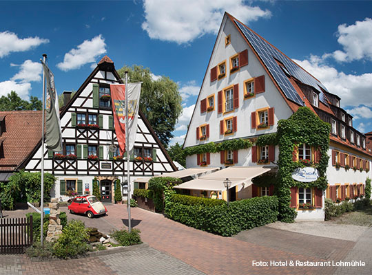 Ansicht von Außen, auf ein Fachwerkshaus, welches hinter einer Gepflasterten Einfahrt steht.