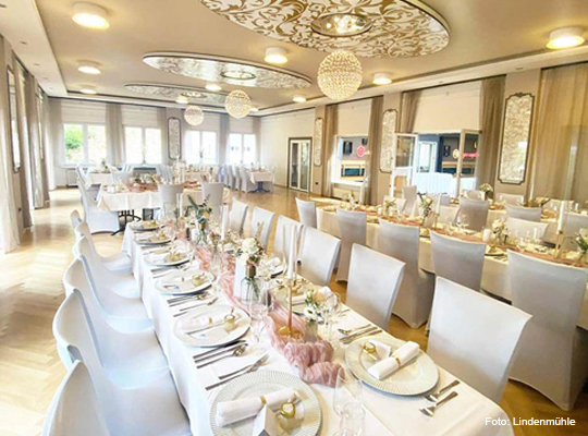 elegant gedeckte Tafeln in hellem Speisesaal 