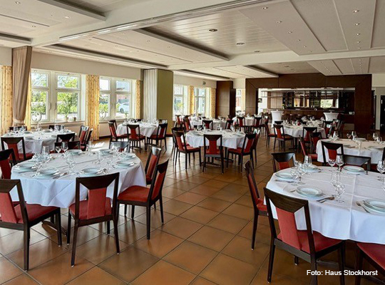 festlich gedeckte, große runde Tische im Gastraum