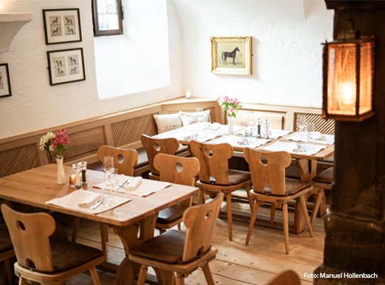eingedeckte Holztische und Pferdebilder an der Wand