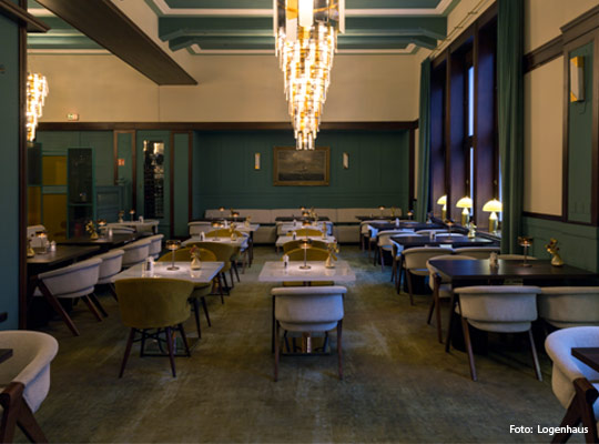 stilvoller Gastraum mit dunkelgrünen Wänden und großer Deckenleuchte