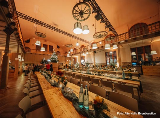 Blick in die großzügige Eventlocation mit langen Speisetafeln