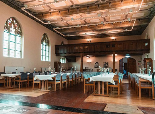 festlich eingedeckte Kulturkapelle mit hölzerner Empore