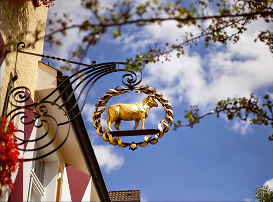 Restaurant-Schild am Eingangsbereich mit einem vergoldeten Lamm 