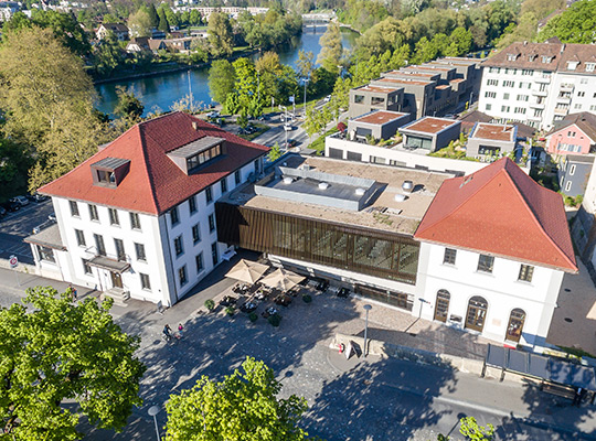 Vogelperspektive auf das große Hotelgebäude mit seinen roten Dächern.