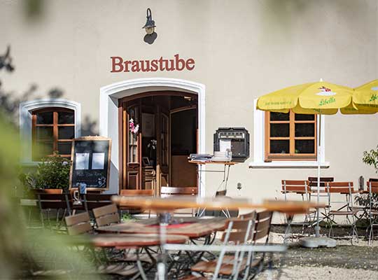 Eingang zum Brauereigasthof mit Blick auf den sommerlichen Biergarten beim Dinnerkrimi