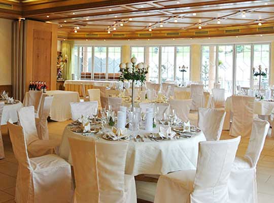 Für einen feierlichen Anlass dekorierter Speisesaal, mit weißen Hussen und schön dekorierten Tischen.