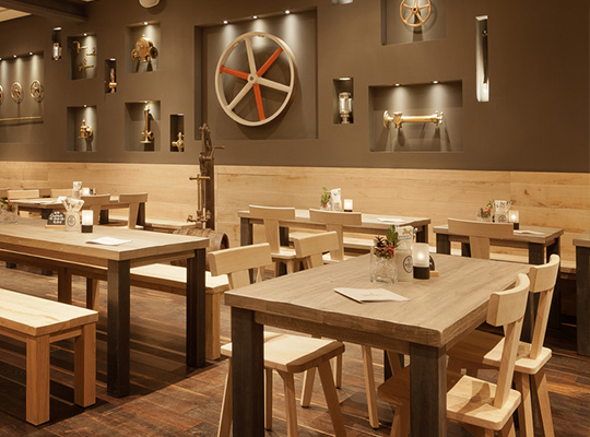 Hochklassig eingerichteter Speisesaal mit einer Steinwand, Holztischen und hochwertigem Holzboden.