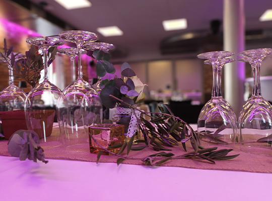 Wein- und Wassergläser auf einem dekorierten Tisch, lila beleuchtet