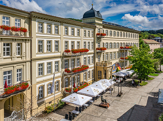 Urig wirkende Außenfassade inklusive schönem Außenbereich mit Sonnenschirmen.