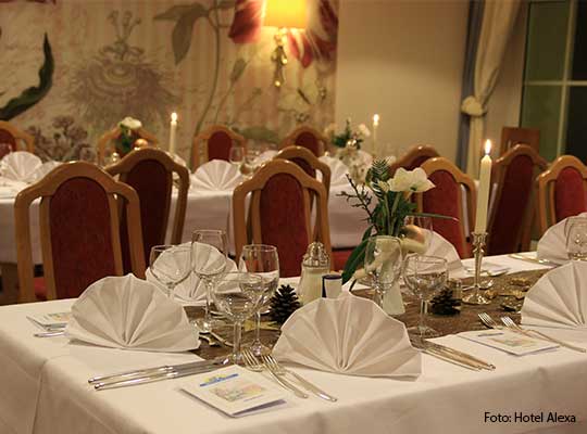 Rote Stühle stehen an einem herzlich gedeckten Tisch, angerichtet für das Dinnerkrimi im Hotel Alexa