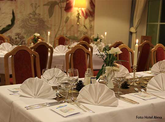 Rote Stühle stehen an einem herzlich gedeckten Tisch, angerichtet für das Dinnerkrimi im Hotel Alexa