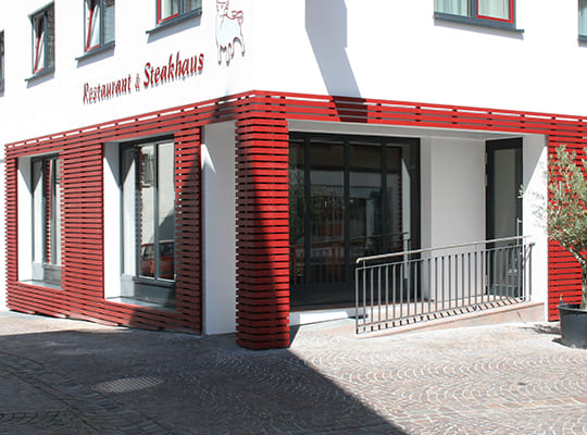 Rot-weiße Außenfassade des Hotel-Restaurants am Eingangsbereich