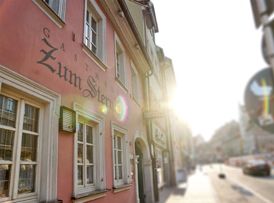 Sonnenstrahlen überfluten die Straßen mit Wärme vor dem Gasthaus-Gebäude