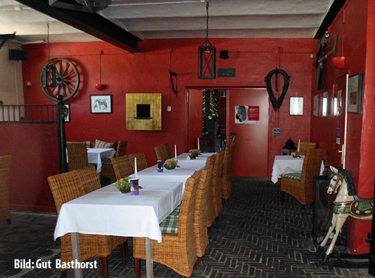 Lange Tischtafel mit weißer Tischdecke und roter Wandfarbe lassen den Raum hell wirken.