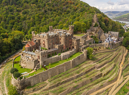 Flugansicht über der schönen Burg Reichenstein mitten im Grün, direkt am Rhein