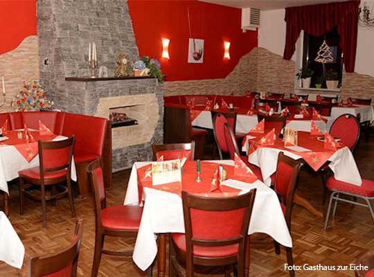 Großer Speisesaal mit roten Stühlen, roten Tischdecken und roter Fassade.