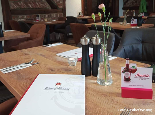 zu sehen ist eine Speisekarte die auf einem Tisch liegt. Der Tisch wurde mit Messern und Gabeln für ein Essen eingedeckt