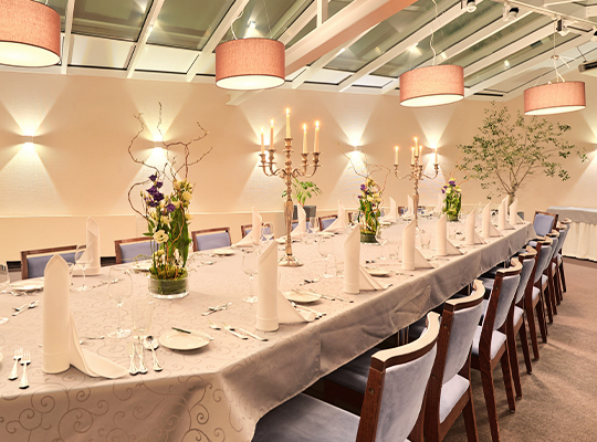 Helle Deckenleuchten strahlen auf eine lange Tischtafel herunter, die bereits für das Dinnerkrimi Bonn angerichtet ist.