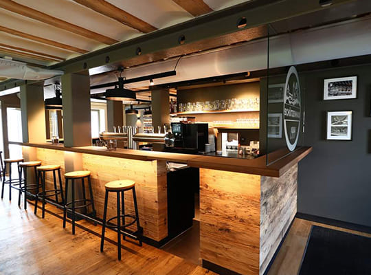Großer einladender Bar-Bereich mit heller Beleuchtung und schöner Holzfassade