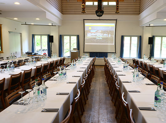 Großer, heller Speisesaal mit 4 komplett durch den Raum verlaufenden Tischtafeln, vorbereitet für das Dinnerkrimi