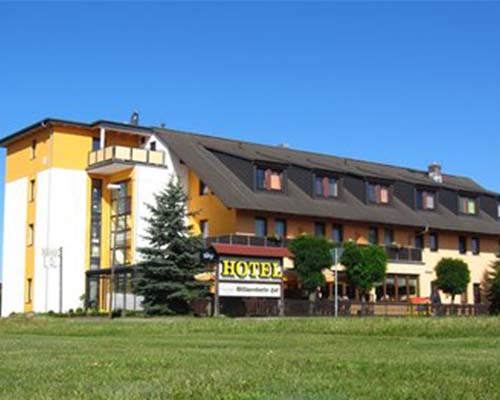 Eindrucksvolles Hotel Gebäude inklusive wunderschön blühender grüner Wiese im Vordergrund