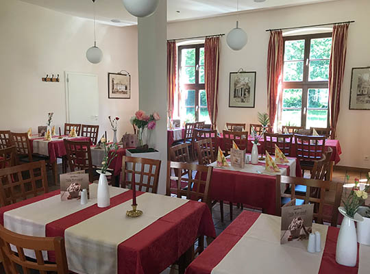 Mit Liebe zum Detail gestalteter Restaurantbereich mit rot-weißen Tischdecken und durch das Sonnenlicht erhellt.