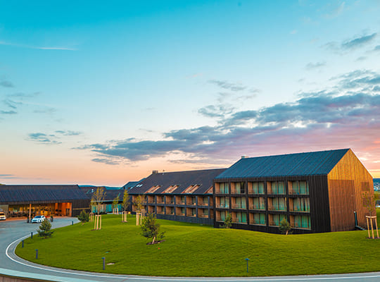 Blick aus der Ferne auf die schöne Hotelanlage inklusive grüner Wiese