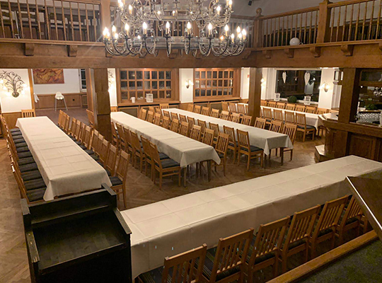 Enorm großer Speisesaal mit riesigem Kronleuchter an der Decke und jeder Menge mit weißen Tischdecken dekorierte Tischtafeln.
