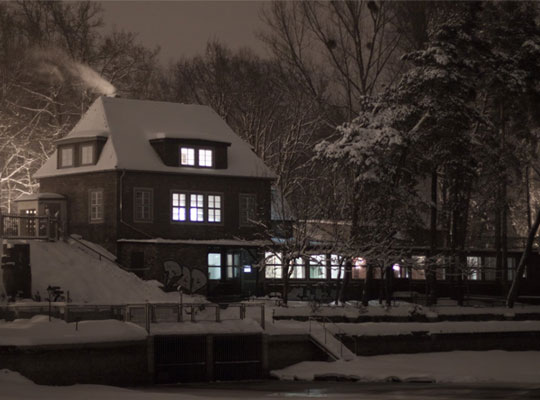 Winterlich gedecktes Haus direkt am zugefrorenen See sorgen für schaurige Stimmung.