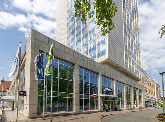 Hochhaus mit großer Glasfront vor blauem Himmel