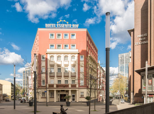 Frontalblick von der Straße auf das zur Hälfte von der Sonne angestrahlte Hotel