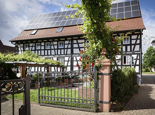 Blick auf das große Gasthausgebäude mit wundervoll gepflegtem Garten mit schönen Zäunen außenrum