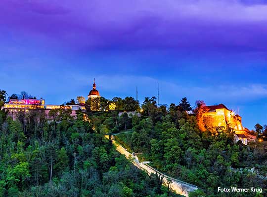 Ausblick auf das Schloss bei Dämmerung, ein Wald im Vordergrund beim Dinnerkrimi Graz