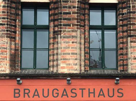 Ansicht der äußeren Fassade des Braugasthaus Gebäudes mit einladendem historischen Schriftzug und Fenstern mit Backsteinumrandung