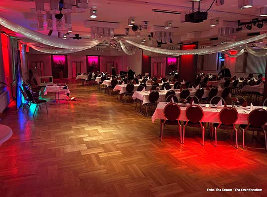 Großer Raum mit Rotem Licht, welches von Strahlern an der Decke aus geht, in Raum mit Laminiertem Boden