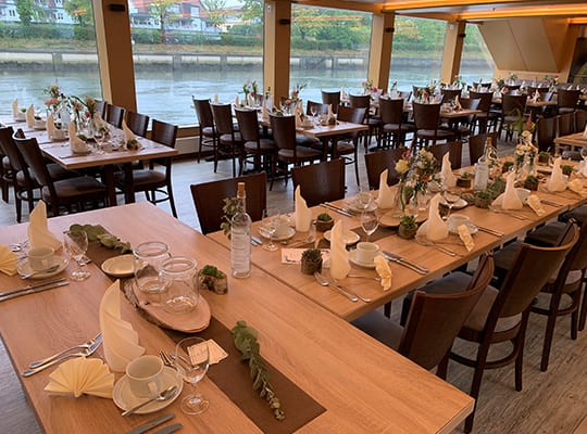 Große Tischtafeln mit wundervollem Blick auf das Wasser um das Boot herum beim Dinnerkrimi Kelheim