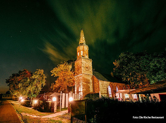 Grüne Lichter am dunklen Himmel und eine leuchtende Kirche