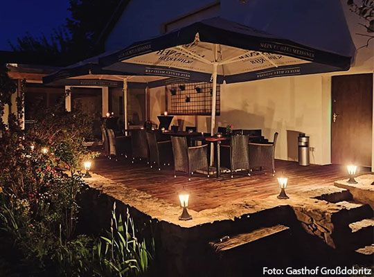 Außen Ansicht einer Trasse bei Nacht, mit angenehmer indirekter Beleuchtung und ein paar Stühlen auf der Terrasse
