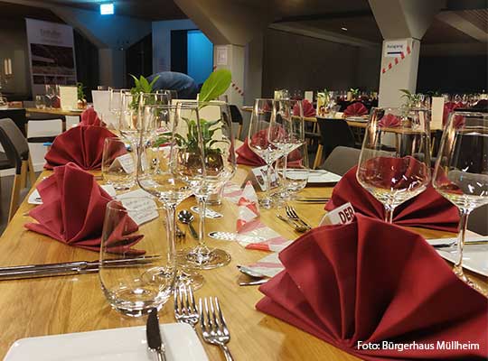 Gedeckter Tisch mit roten Servietten, Besteck und Gläsern beim Dinnerkrimi