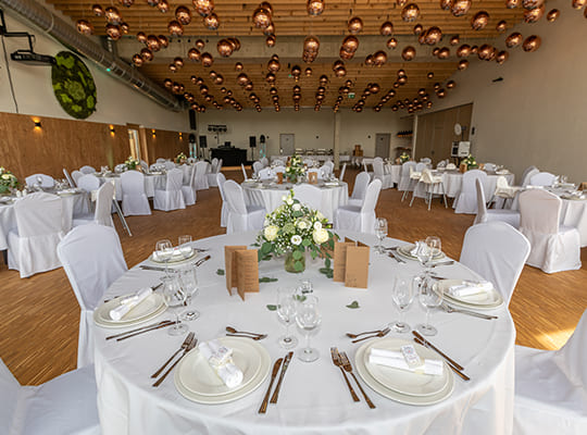 Stilvoll eingerichteter Veranstaltungssaal mit beeindruckender Deckengestaltung und schönen runden Tischen mit liebevoller Dekoration