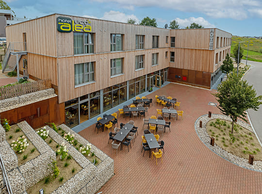 Seitliche Ansicht des Alea Eco Hotels von außen, mit wunderschönem Außenbereich und Hof und toller Fassade aus Holz und Glas