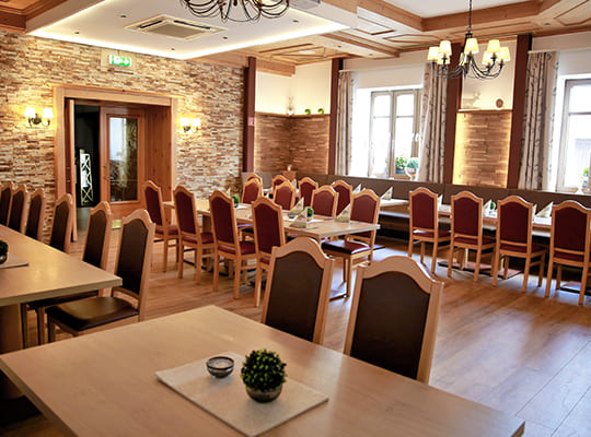 Großer Veranstaltugs- und Speisesaal mit schönen und schlichten Dekorationen auf den Tischen in gemütlicher Beleuchtung